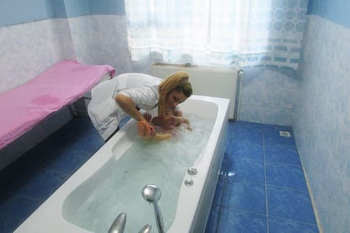 Hidroterapi ünitesinde terapist eşliğinde su içi egzersiz yapan çocuk