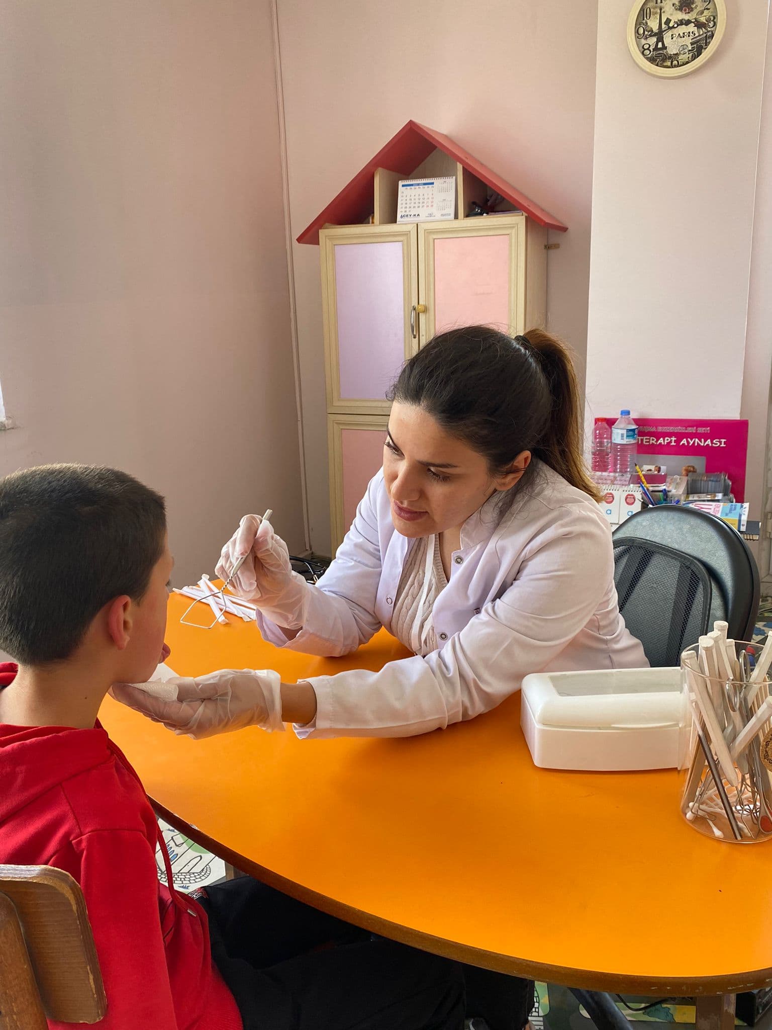 Dil terapisi ünitesinde Terapi Aynası önünde ağız ve çene hareketlerini çalışan terapist ve çocuk